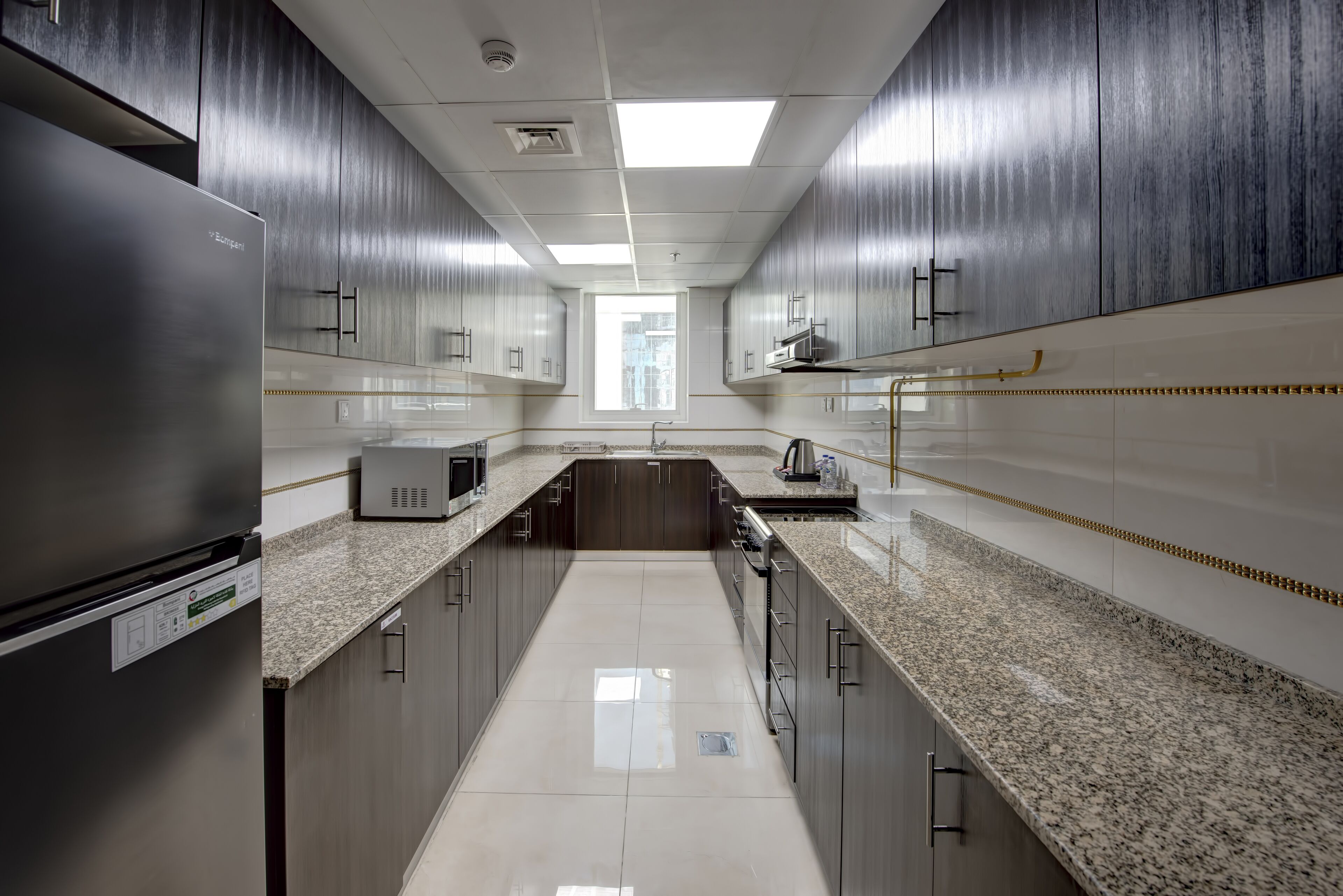 A modern kitchen with dark wood cabinets, granite countertops, and stainless steel appliances.