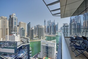 Un edificio de gran altura con un balcón que ofrece vistas a un paisaje urbano, con arquitectura moderna y una vista de agua.