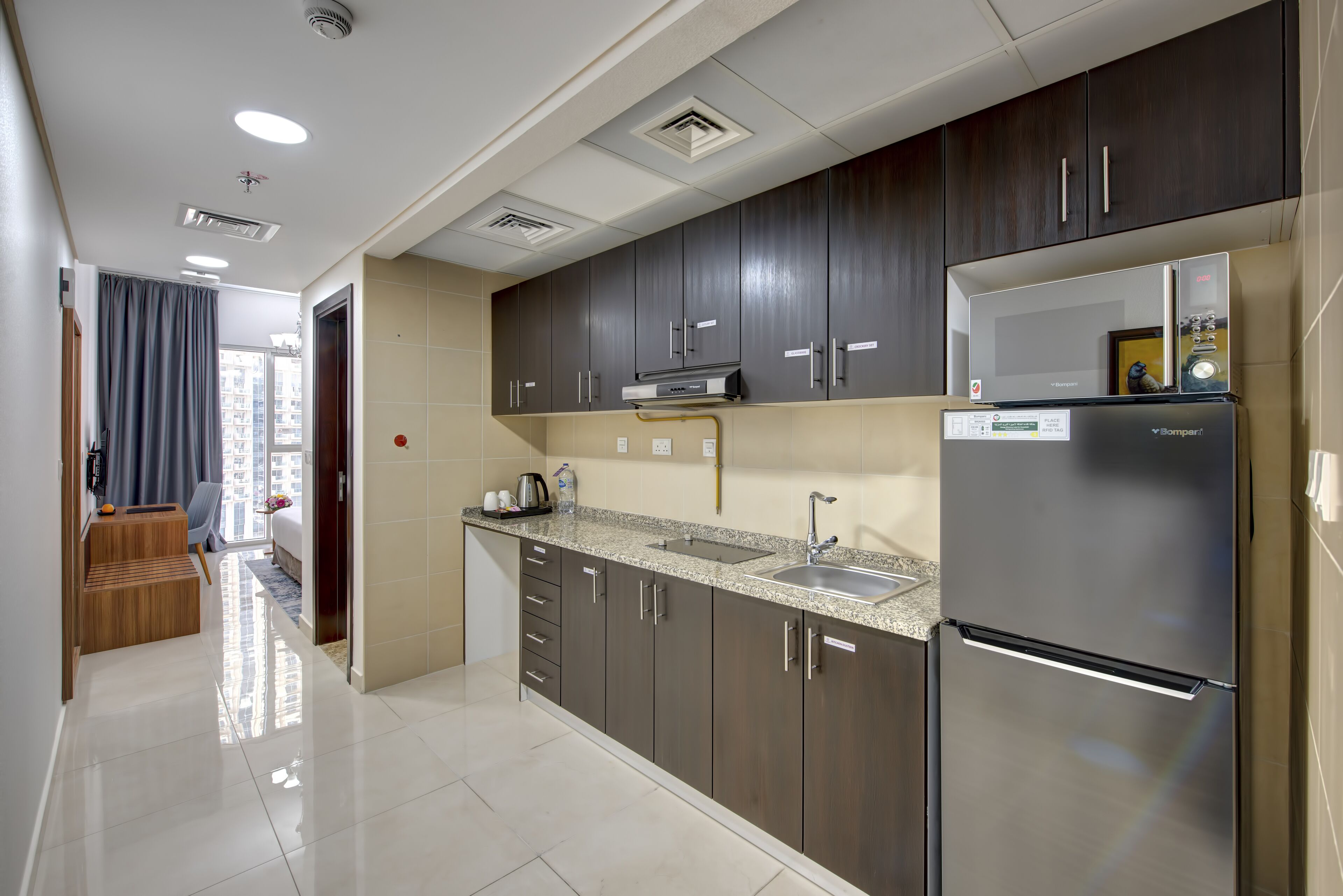 A modern kitchen with dark cabinets, a stainless steel refrigerator, and a built-in microwave.