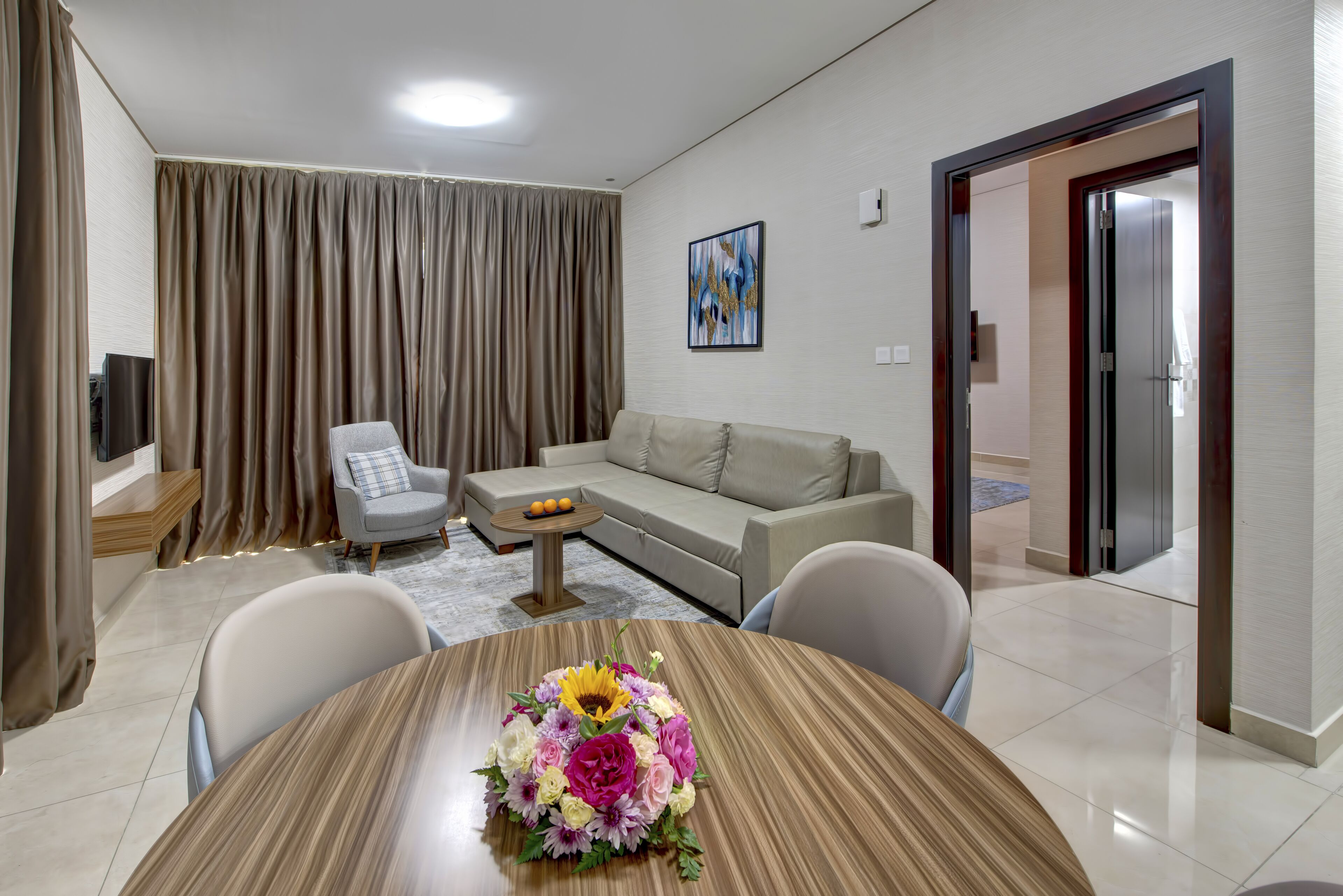 Una sala moderna con una mesa de comedor de madera, un sofá y un televisor.