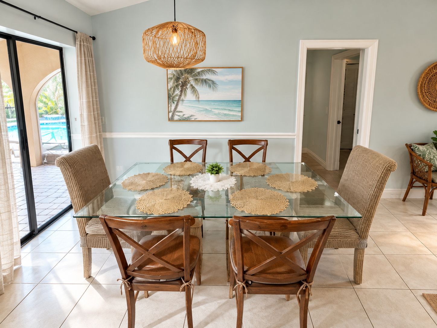 A dining area with a glass table, woven placemats, and wicker chairs.