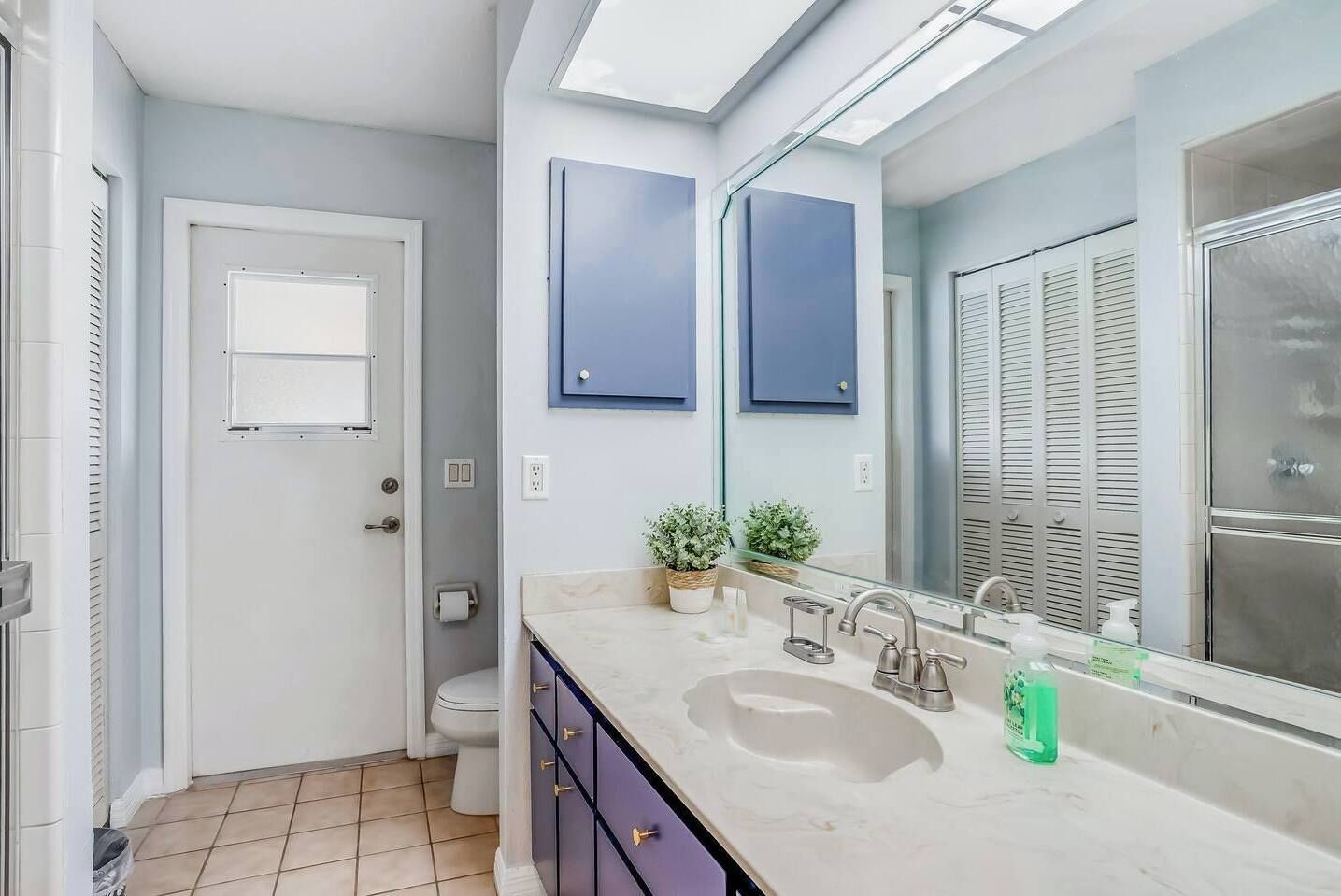 A modern bathroom with a large mirror, a sink with a vanity, and a toilet.