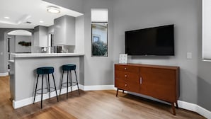 Een moderne keuken met een bar, een grote flatscreen-televisie en een houten kast.