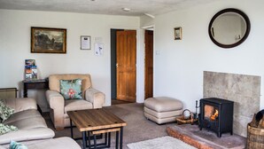 A living room with a sofa, armchair, ottoman, coffee table, fireplace, and a mirror on the wall. - 3 bedroom accommodation in Carlisle (Carlisle)