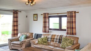 A living room with a sofa set, a coffee table, and plaid curtains. - 3 bedroom accommodation in Carlisle (Carlisle)