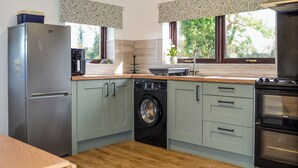 A modern kitchen with a stainless steel refrigerator, a washing machine, and a built-in oven. - 3 bedroom accommodation in Carlisle (Carlisle)