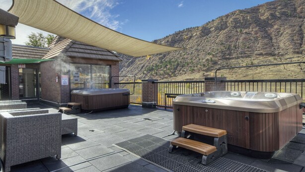 An outdoor hot tub area with seating and a view of a mountainous landscape.