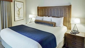 A hotel room with a large bed, two bedside tables, a headboard, and a framed picture on the wall.
