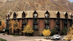 A multi-story hotel with a brick facade and a mountain backdrop.