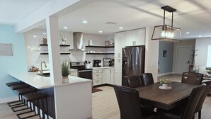 Una cocina moderna con armarios blancos, una campana extractora de acero inoxidable y una isla integrada con taburetes de bar.