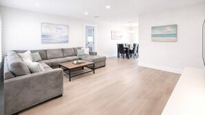 Una sala de estar moderna con un sofá gris, una mesa de centro y una zona de comedor con sillas y una mesa.