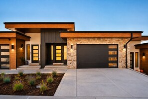 A modern two-story house with a stone facade, a dark garage door, and a well-maintained front yard. - Incredible Views | 2 Kitchens | 3 Living Rms | Lake Access (Hideout)