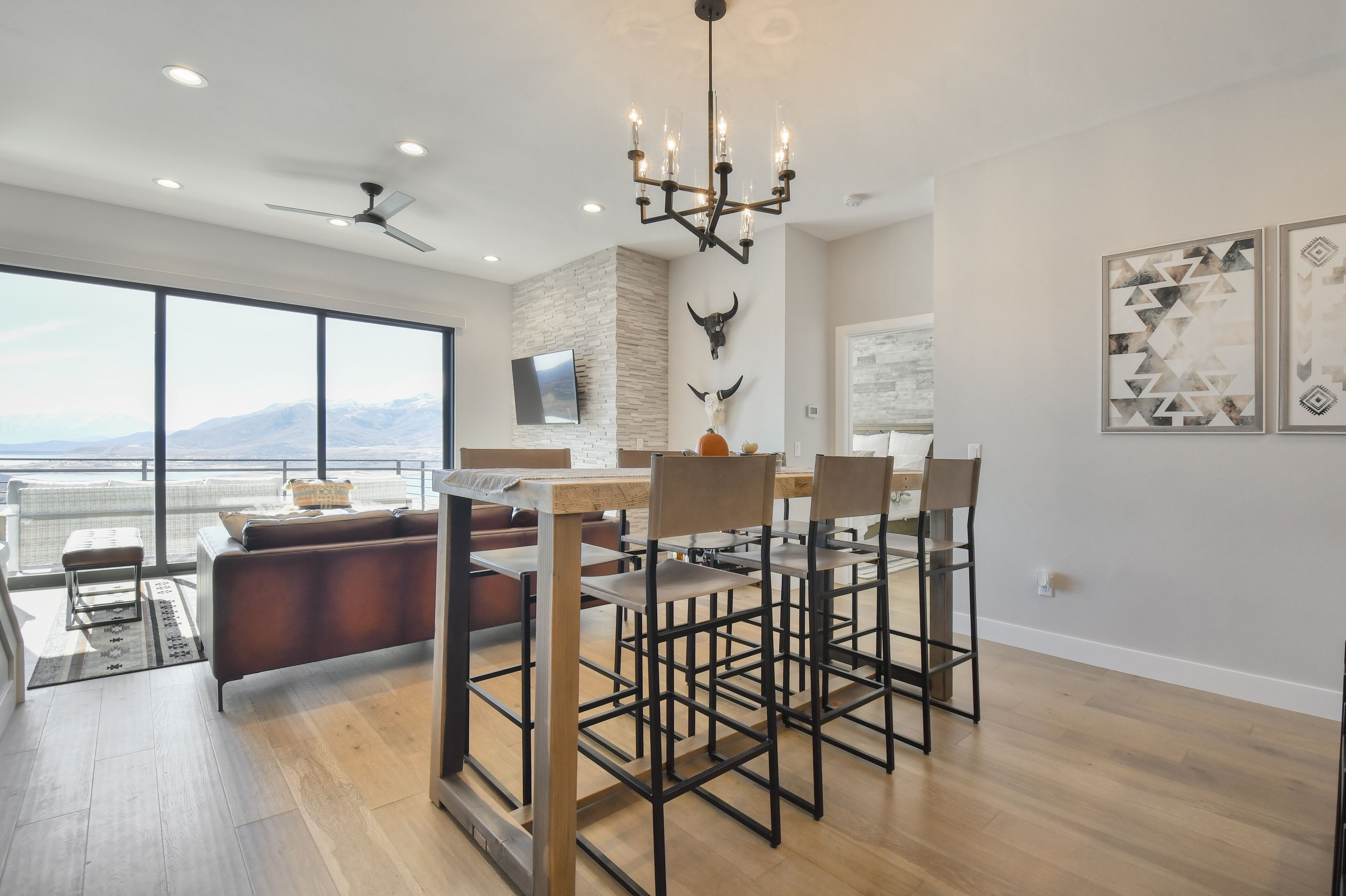 A modern kitchen with a dining area, large windows, and a view of mountains.