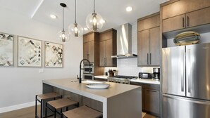 Una cocina moderna con una isla central, electrodomésticos de acero inoxidable e iluminación colgante.