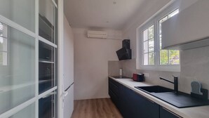 A modern kitchen with a built-in oven, a window, and a black range hood. - Beach la gravière Villa F4 between Lake and Sea with reversible air conditioning in Hossegor (SOORTS HOSSEGOR)
