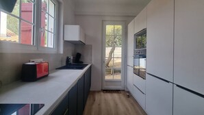 A narrow kitchen with a window, a toaster, and a door leading outside. - Beach la gravière Villa F4 between Lake and Sea with reversible air conditioning in Hossegor (SOORTS HOSSEGOR)