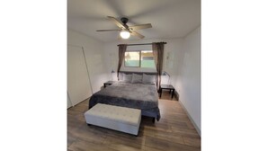 A bedroom with a bed, a bench, a ceiling fan, and a window with curtains. - Msg for 5%off_2Bed1Bath KingQueenBeds NorthPHX (Phoenix)