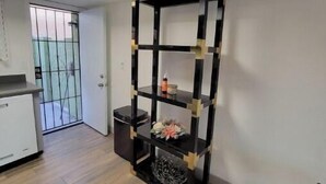A corner room with a black and gold shelving unit, a small white cabinet, and a wooden floor. - Msg for 5%off_2Bed1Bath KingQueenBeds NorthPHX (Phoenix)