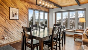 A dining area with a wooden table and chairs, large windows with a view, and a ceiling with exposed beams. - Private Hot Tub! Close to Slopes! On Free Shuttle Route! (Steamboat Springs)
