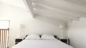 Un dormitorio con una cama grande, dos mesitas de noche y una puerta de listones de madera.