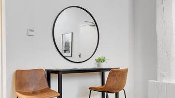 A room with a round mirror, two chairs, a small table, and a potted plant.