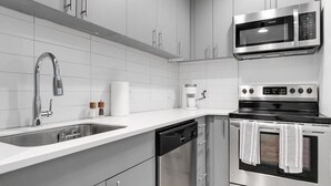 A modern kitchen with stainless steel appliances, a dishwasher, and a coffee maker. - Downtown Living in Richmond's Amazing Shockoe Bottom (Richmond)