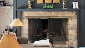 A room with a stone fireplace, a chandelier, and decorative items on the mantel. - Waterfront Home at the  River Haven Sanctuary (Richmond)
