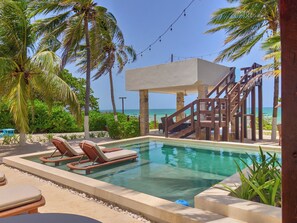 Un'area piscina con lettini, una zona relax coperta e vista sull'oceano.