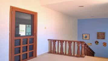 A hallway with a wooden door, a staircase with a wooden railing, and a blue wall with decorative items.
