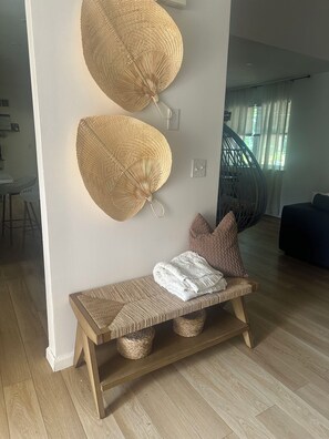 A room with a woven bench, two wall-mounted woven lamps, a cushioned bench with a white throw, and a staircase in the background. - Experience Nature In Comfort (Tobyhanna)