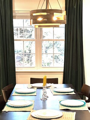 Una mesa de comedor dispuesta con platos, una vela y posavasos.