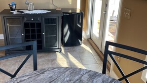 Une cuisine dotée d’un plan de travail en marbre, d’un réfrigérateur noir et d’un téléviseur à écran plat fixé au mur.