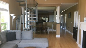 Un vaste salon doté d’un canapé d’angle gris, d’une table basse en bois et d’un escalier en colimaçon menant à un étage supérieur.