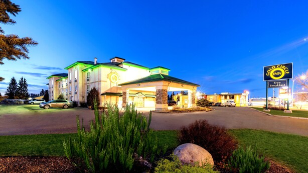 Un hotel con un tetto verde, un cartello che indica la colazione gratuita e un ingresso ben illuminato.