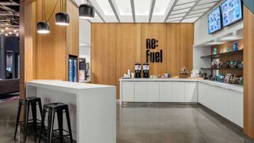 A modern cafe interior with a wooden accent wall, a counter with stools, and a menu display.