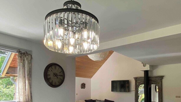 A dining area with a wooden table, bench, chandelier, and a cozy seating area with a sofa and cushions. - SUPERB HOUSE, GREAT LOCATION - SLEEPS 10 (Allemont)