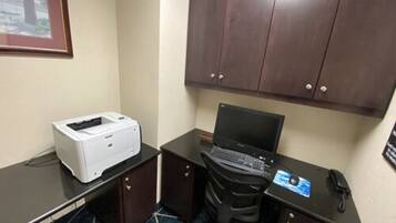 A small office space with a desk, a printer, a laptop, and a telephone.