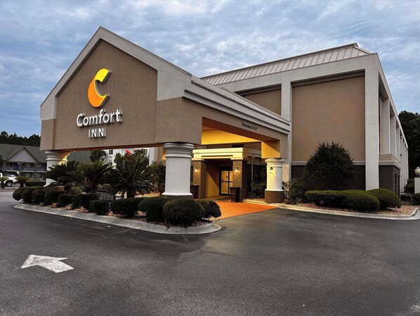 A Comfort Inn hotel with a modern design, featuring a prominent 'Comfort Inn' sign, a covered entrance, and a parking lot.