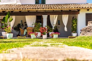 A covered outdoor area with a tiled roof, potted plants, and a pathway leading to a building entrance. - Impressive villa within walking distance to Pollensa (Pollensa / Pollença)