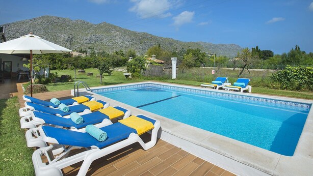 A swimming pool with lounge chairs and a pergola with an umbrella.
