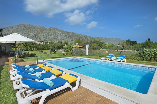 A swimming pool with lounge chairs and a pergola with an umbrella.