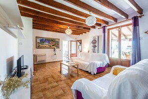 A room with a wooden ceiling, a white sofa, a small table, a TV, and a painting on the wall. - Impressive villa within walking distance to Pollensa (Pollensa / Pollença)