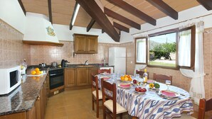 A kitchen with wooden cabinets, a stove, and a dining table set for four with a patterned tablecloth.