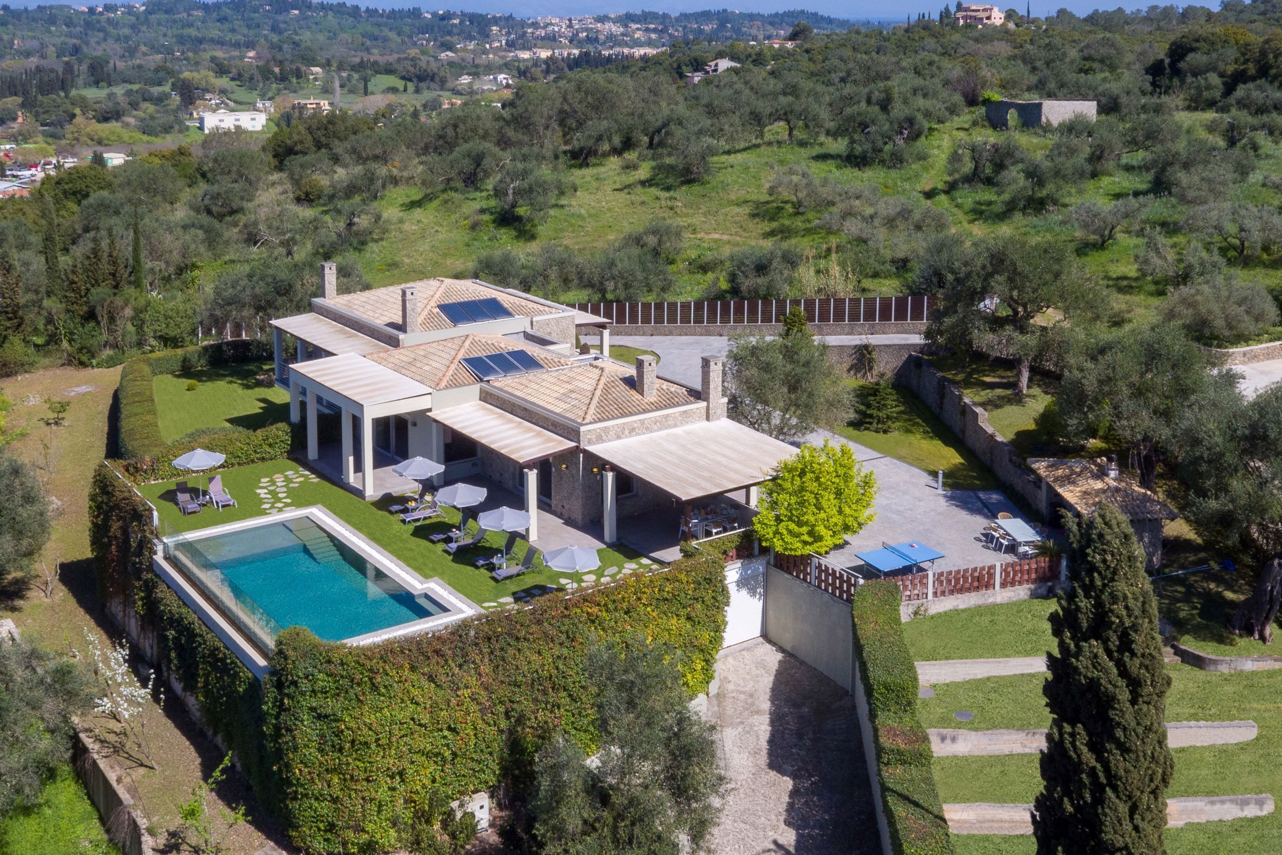 A modern villa with a swimming pool, outdoor seating, and solar panels.