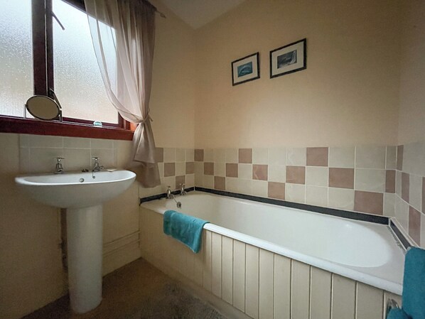 A bathroom with a sink, a bathtub, and two framed pictures on the wall. - 3 bedroom accommodation in Kinlochbervie (Kinlochbervie)