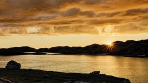 A sunset over a lake with mountains in the background.