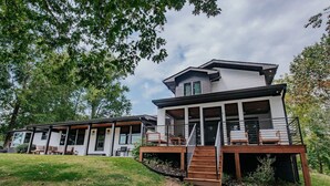 Ein modernes, zweistöckiges Haus mit einer Veranda und einer Treppe, die zu einer Terrasse führt.