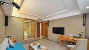 Une chambre d’hôtel moderne équipée d’un canapé, d’un bureau, d’une télévision et d’une porte coulissante donnant accès à la salle de bain.