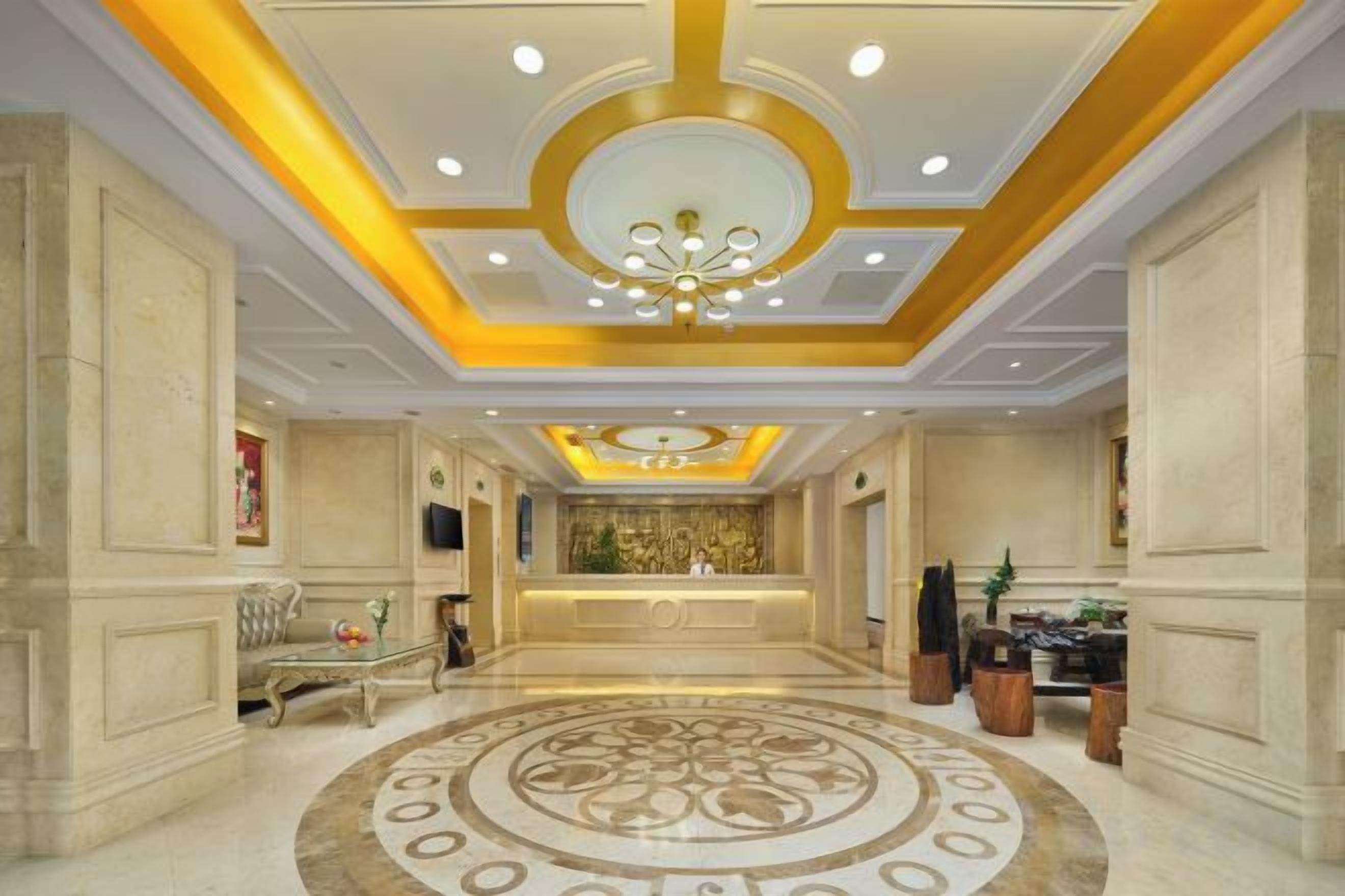 Vestíbulo de hotel con mostrador de recepción, candelabro y piso estampado.