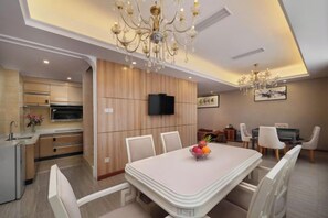 A modern kitchen with built-in appliances, a dining area with a white table and chairs, and a chandelier. - Vienna 3 Best Hotel (Yangchun Bus Station) (Yangchun)